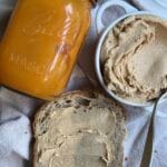 Pumpkin spice butter with sourdough bread and jar on a linen background.