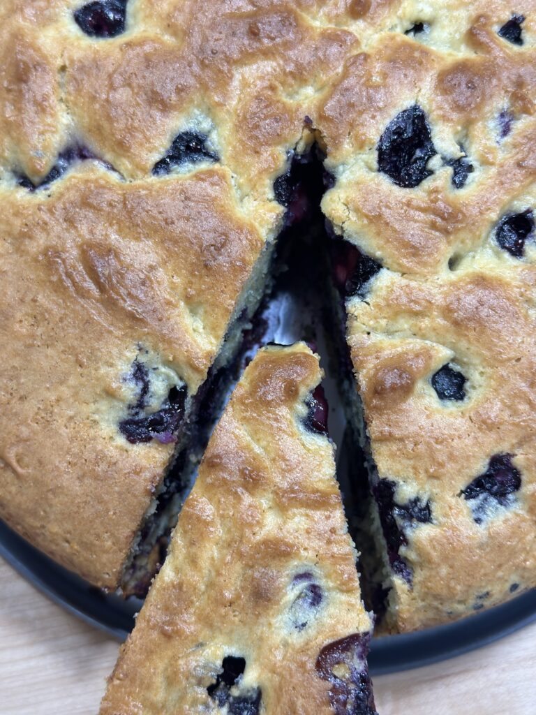 Top view of a freshbackedbluberry cake with single slice being removed