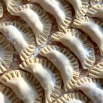 Homemade dumplings on a wooden board, ready to cook