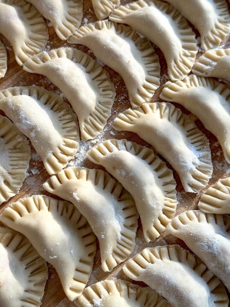 Homemade dumplings on a wooden board, ready to cook