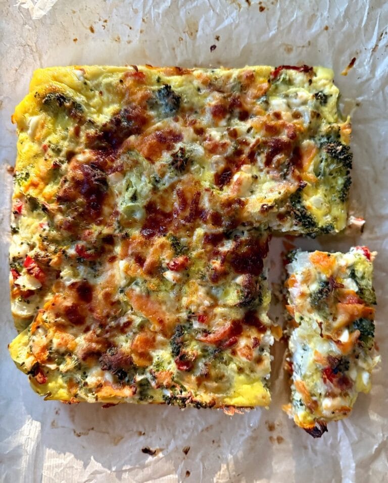 Golden baked veggie and feta egg casserole with broccoli, carrot, and red pepper in a square pan.